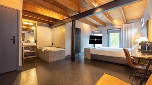 Une chambre d’hôtel moderne dotée d’un grand lit, d’une salle de bain séparée avec baignoire, d’un bureau avec une chaise et d’une télévision.