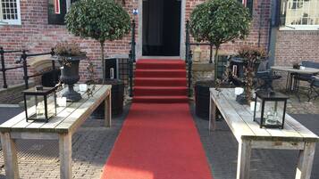 A red carpet leading to a building entrance with brick walls and black-framed windows.