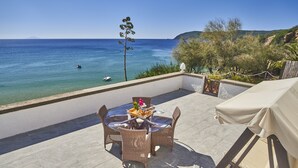 Una terraza con mobiliario de mimbre, una mesa con bandeja y vista al mar.
