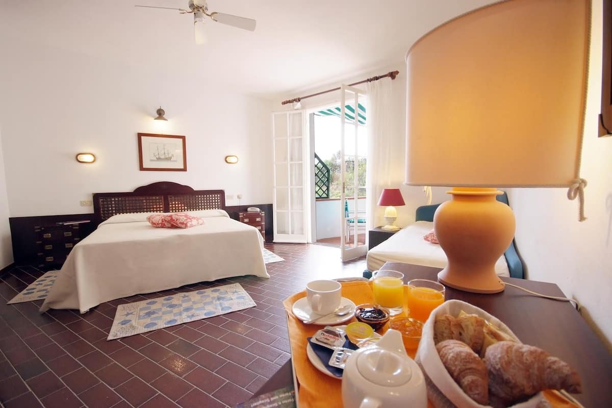 A hotel room with a bed, breakfast tray, and a balcony with a view.