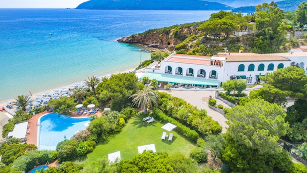 Un resort con piscina, playa y vistas a la montaña.
