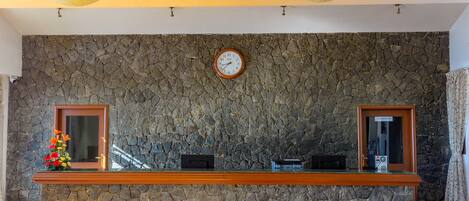 A reception area with a stone wall, a clock, and a reception desk.