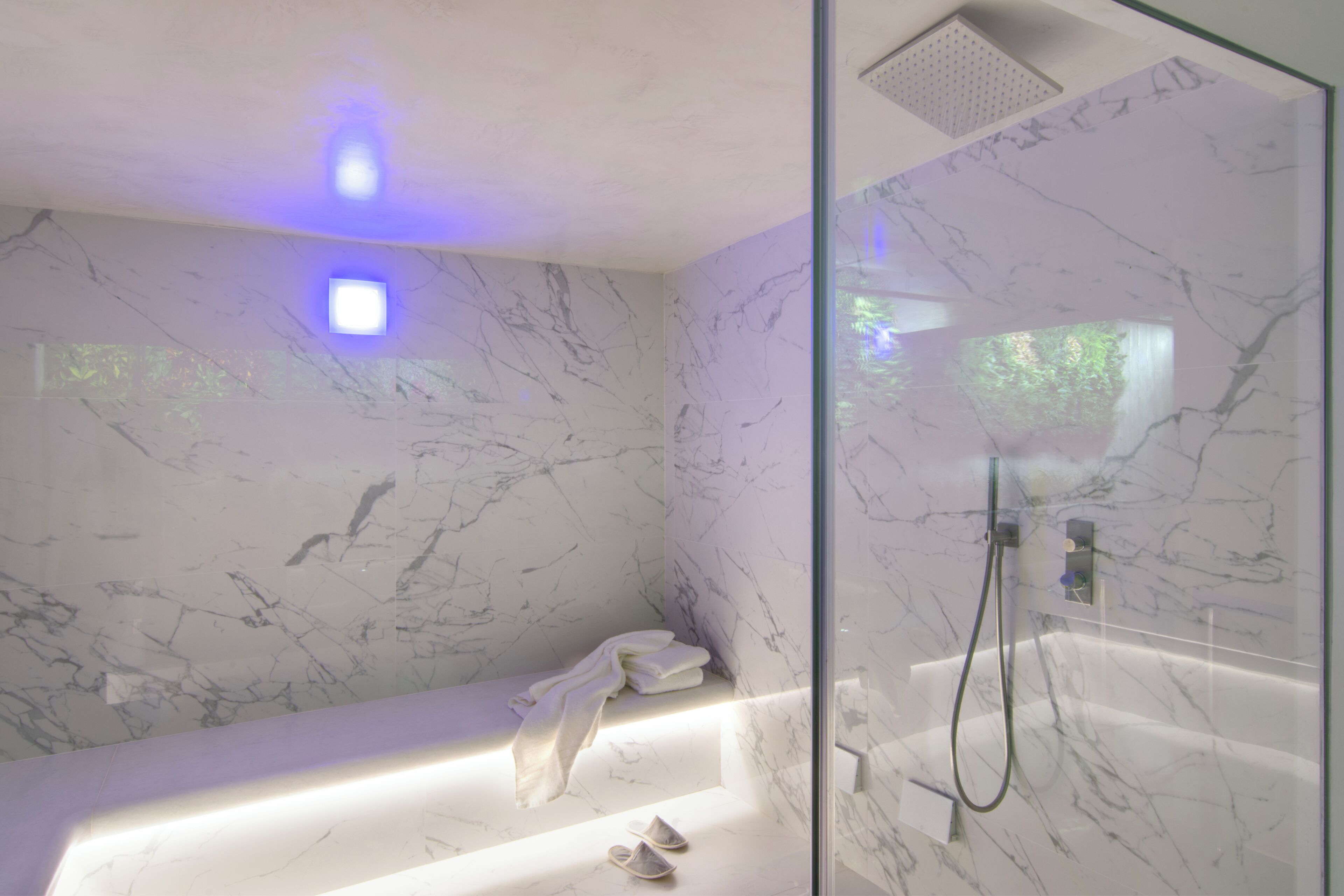 Une salle de bain moderne avec un mur en marbre, une douche à l’italienne et une baignoire intégrée.