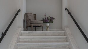Una escala amb graons de marbre blanc, una cadira i un vas amb flors.