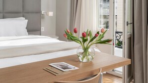 Habitació d'hotel amb un llit, una taula de nit de fusta amb un vas de tulipes, i una vista de la ciutat per la finestra.