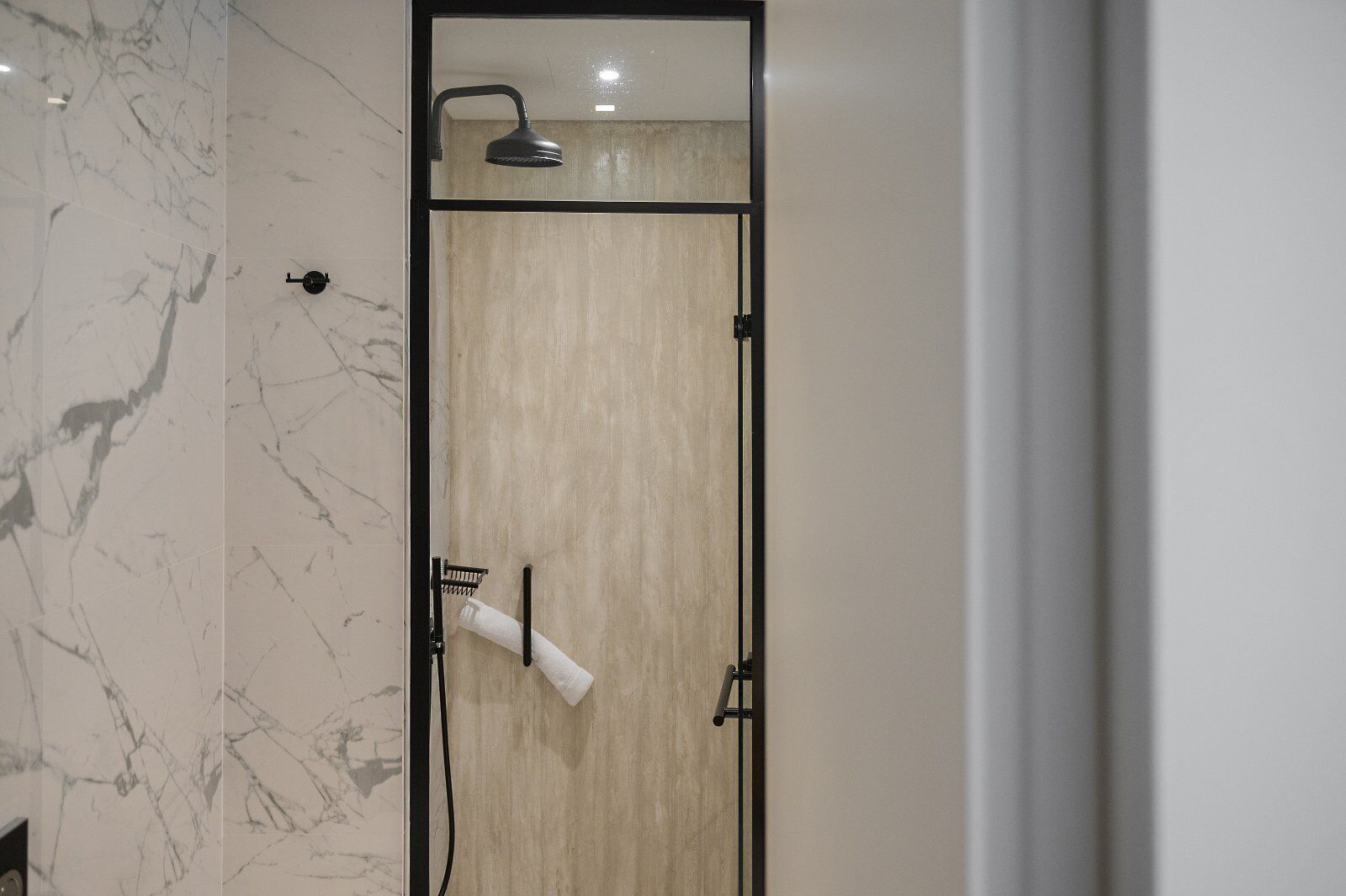 Un baño con puerta de madera, cabezal de ducha y un perchero.