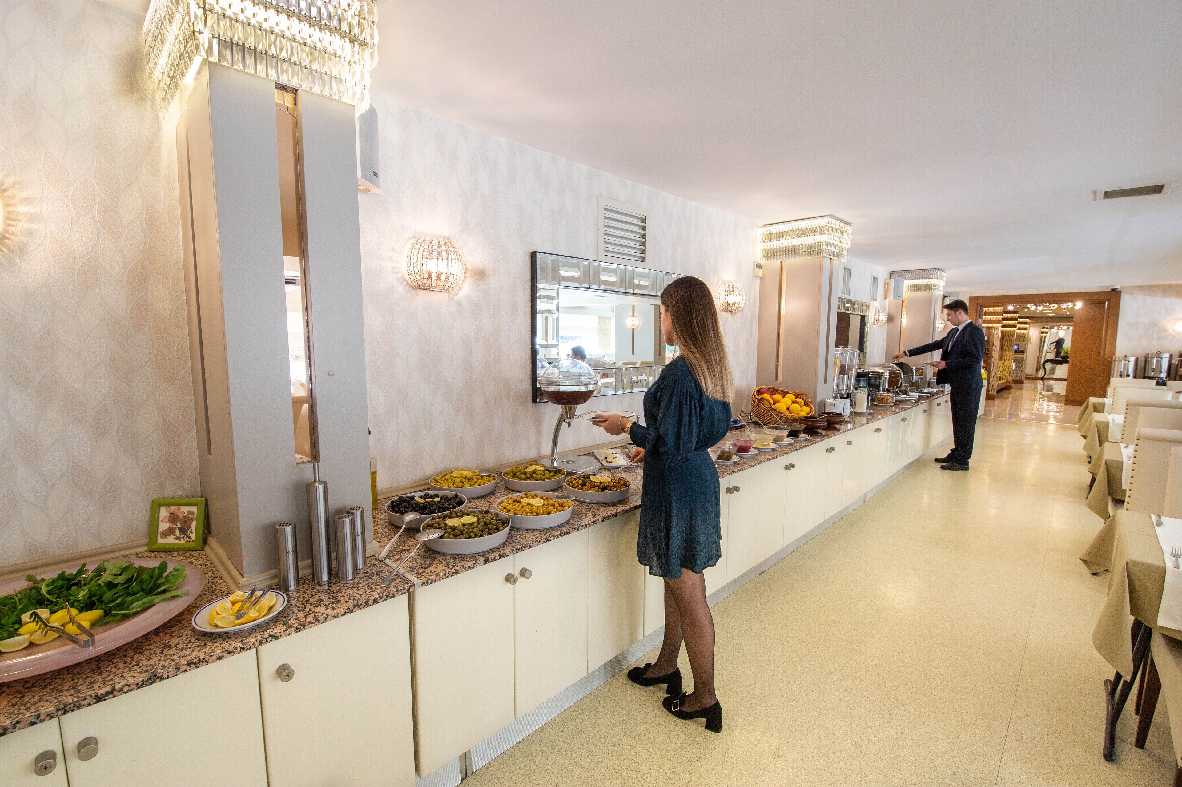 A buffet setup with various food items and a person serving.