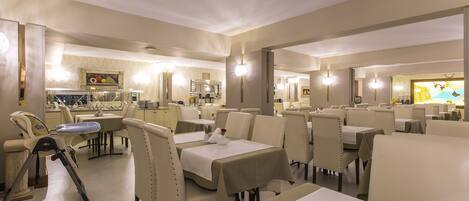 A restaurant with multiple tables and chairs, a dining area, and a kitchen in the background.