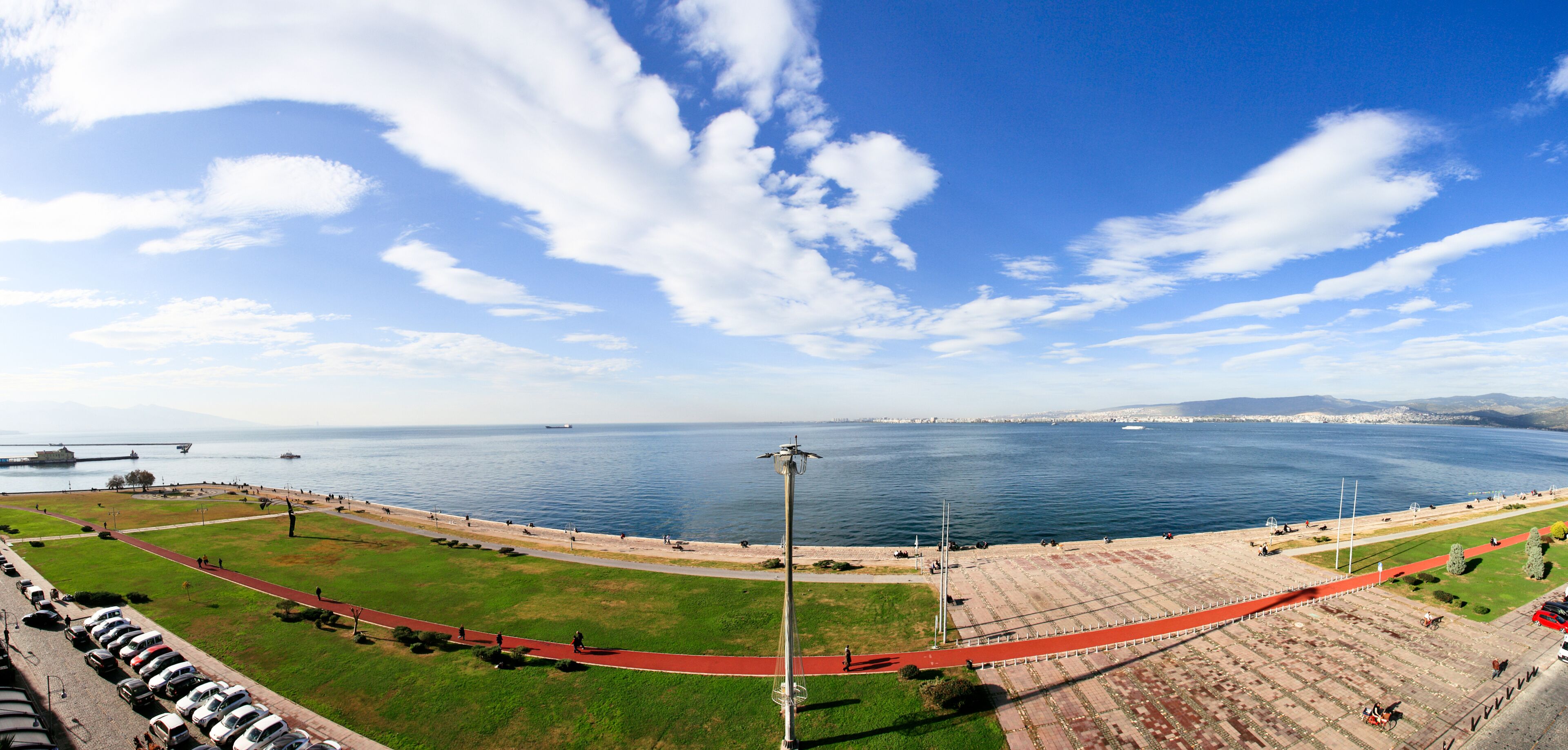 Un parque costero con una pista de atletismo roja, zonas verdes abiertas y vistas al mar.