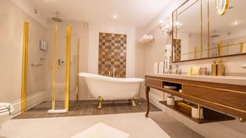 A luxurious bathroom with a freestanding bathtub, a walk-in shower with golden accents, and a large mirror with a gold frame.