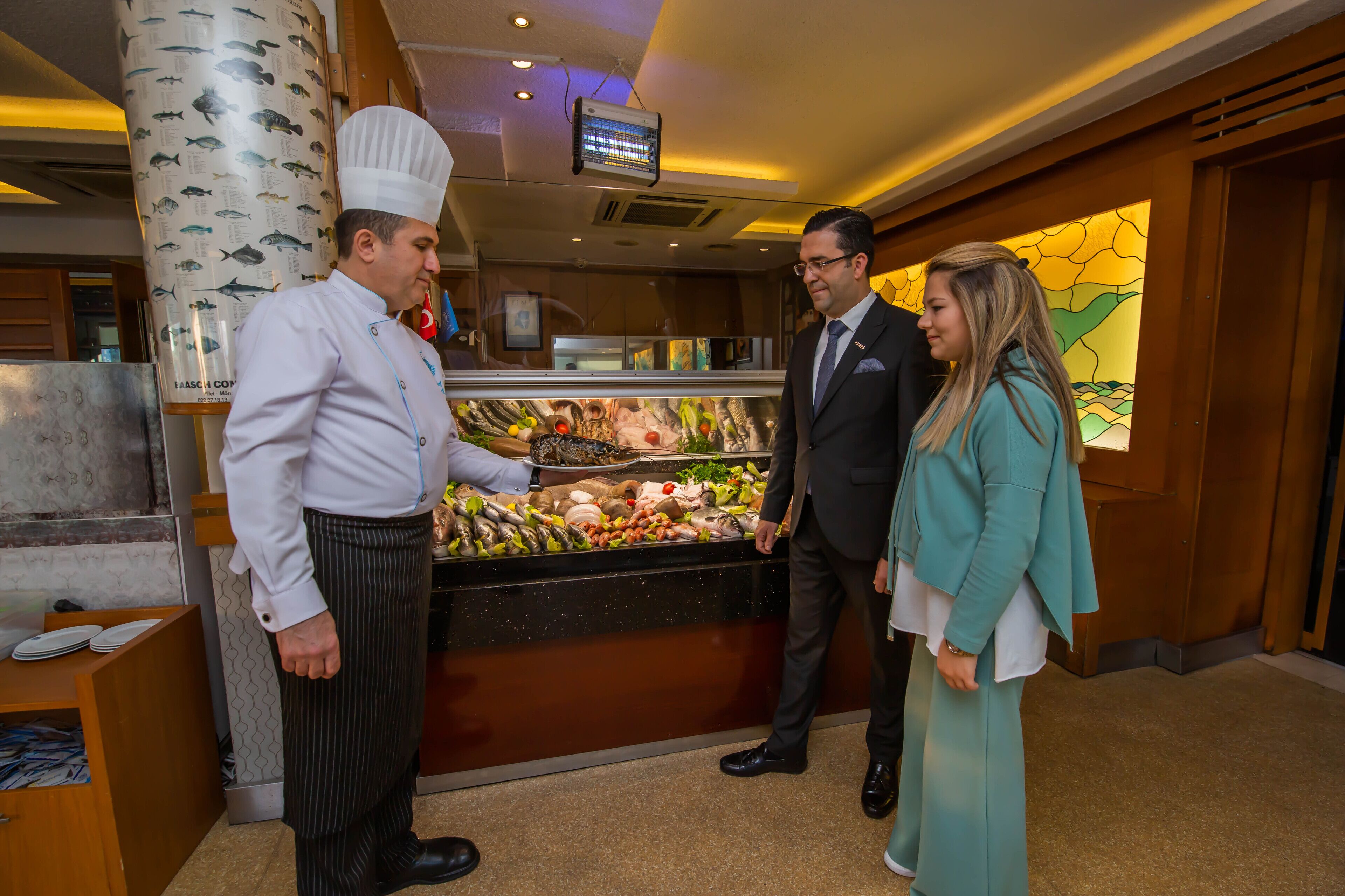 A hotel lobby with a seafood display, a television mounted on the wall, and a wooden reception desk.