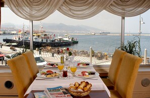 A table set for breakfast with a view of the sea and boats. - Kilim Otel Izmir (Izmir)