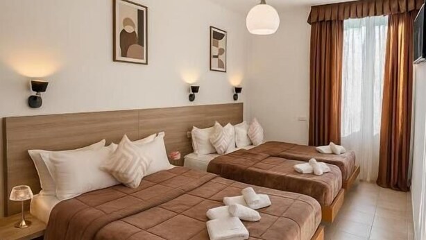 Una habitación de hotel con dos camas, una mesita de noche, una lámpara y una luz en el techo.