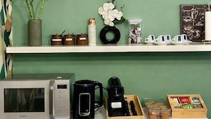 Una kitchenette equipada con microondas, cafetera y juego de té.