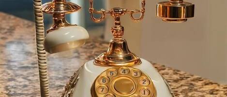 A vintage rotary dial telephone on a granite countertop.