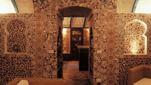 A room with mosaic tile walls, a central archway, and wicker furniture.