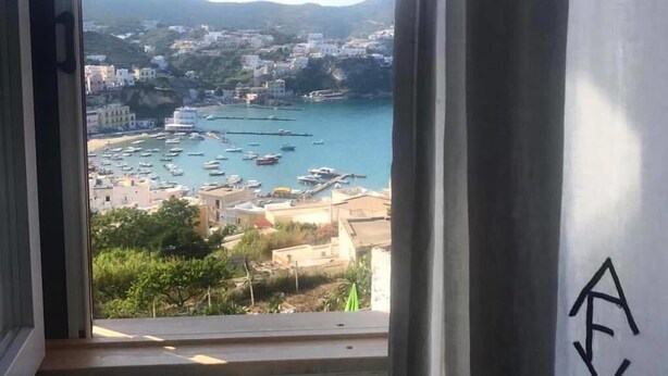 A view from a window overlooking a marina with boats, buildings, and hills in the distance.