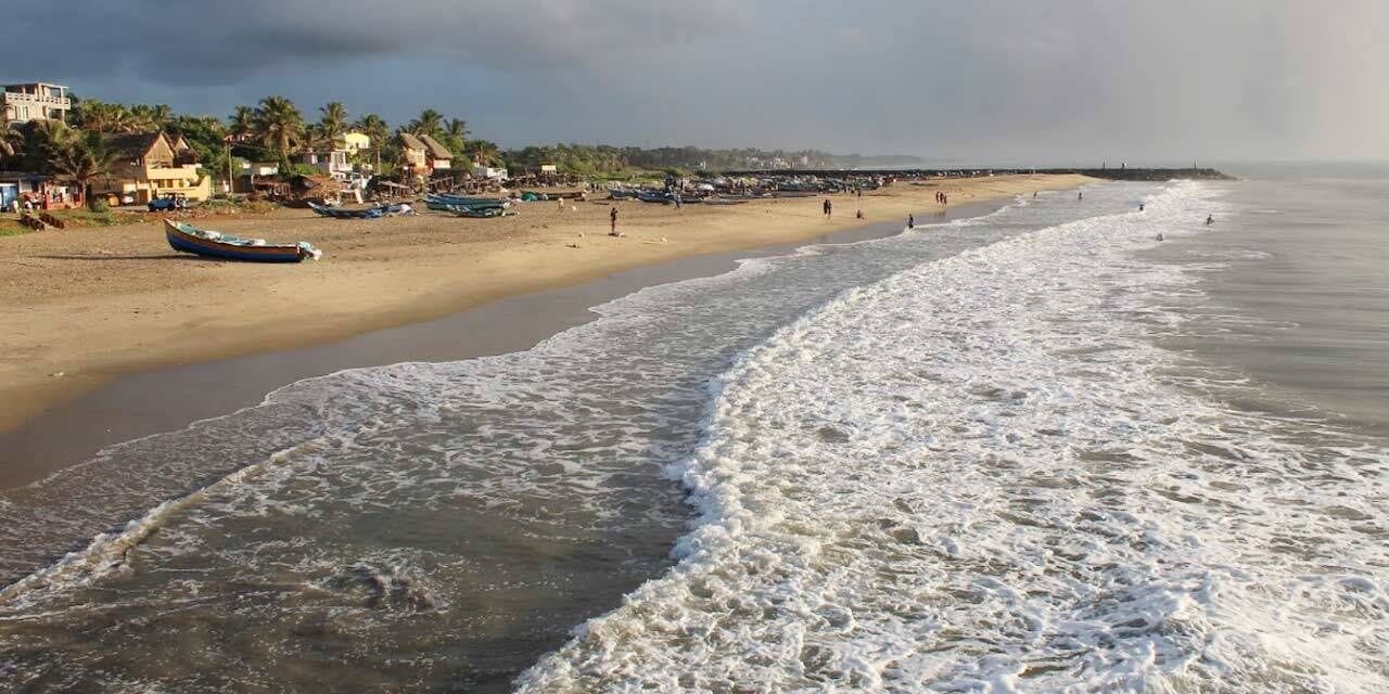 A beach with boats, a sandy shore, and buildings in the background.
