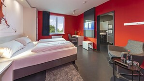 Una habitación de hotel moderna con una cama grande, un escritorio, una silla y un televisor.