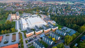 Vista aérea de una moderna instalación educativa con varios edificios, zonas de estacionamiento y barrios residenciales circundantes.