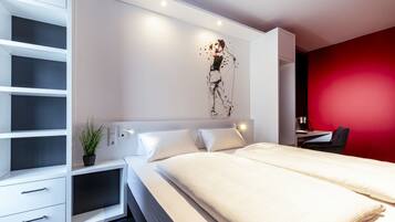 Un dormitorio moderno con cama, mesitas de noche, un escritorio y una pared de acento en rojo.