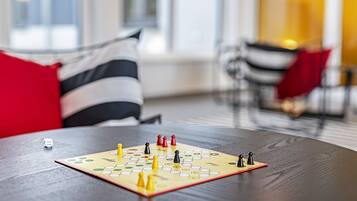 Un juego de mesa sobre una mesa de madera en una habitación con almohadones a rayas y un cojín rojo.