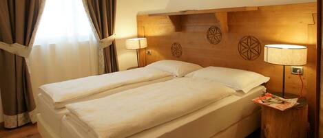 A double bed with a wooden headboard, two bedside lamps, and a wooden floor.