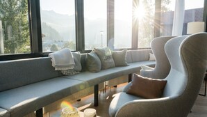 A modern interior with a bench and armchair by a large window overlooking a mountainous landscape. - meiZeit Lodge (Filzmoos)