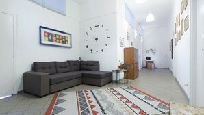 A modern living room with a gray sectional sofa, a patterned rug, a wall clock, and a framed picture.