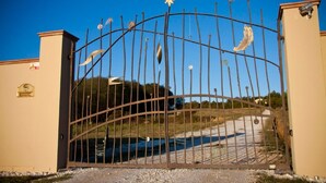 Una entrada cerrada con un portón metálico decorativo que presenta un emblema de sol y una placa en la pared.