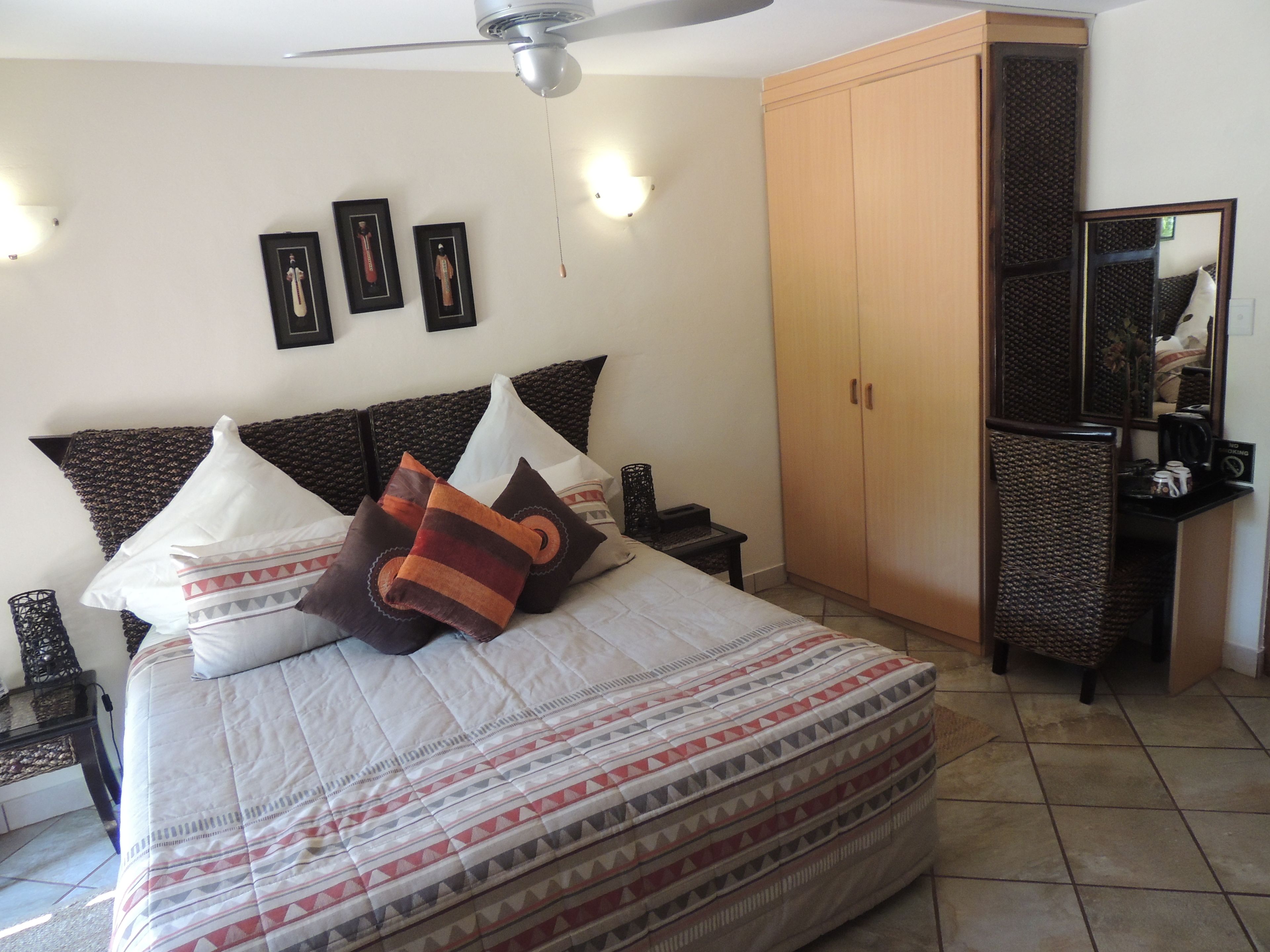 A bedroom with a bed, a wardrobe, a nightstand, a mirror, and wall-mounted lights.