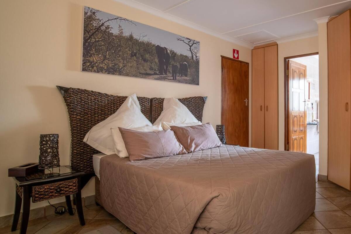 Ein Schlafzimmer mit einem großen Bett, einem Nachttisch, einem Holzschrank und einem Gemälde an der Wand.