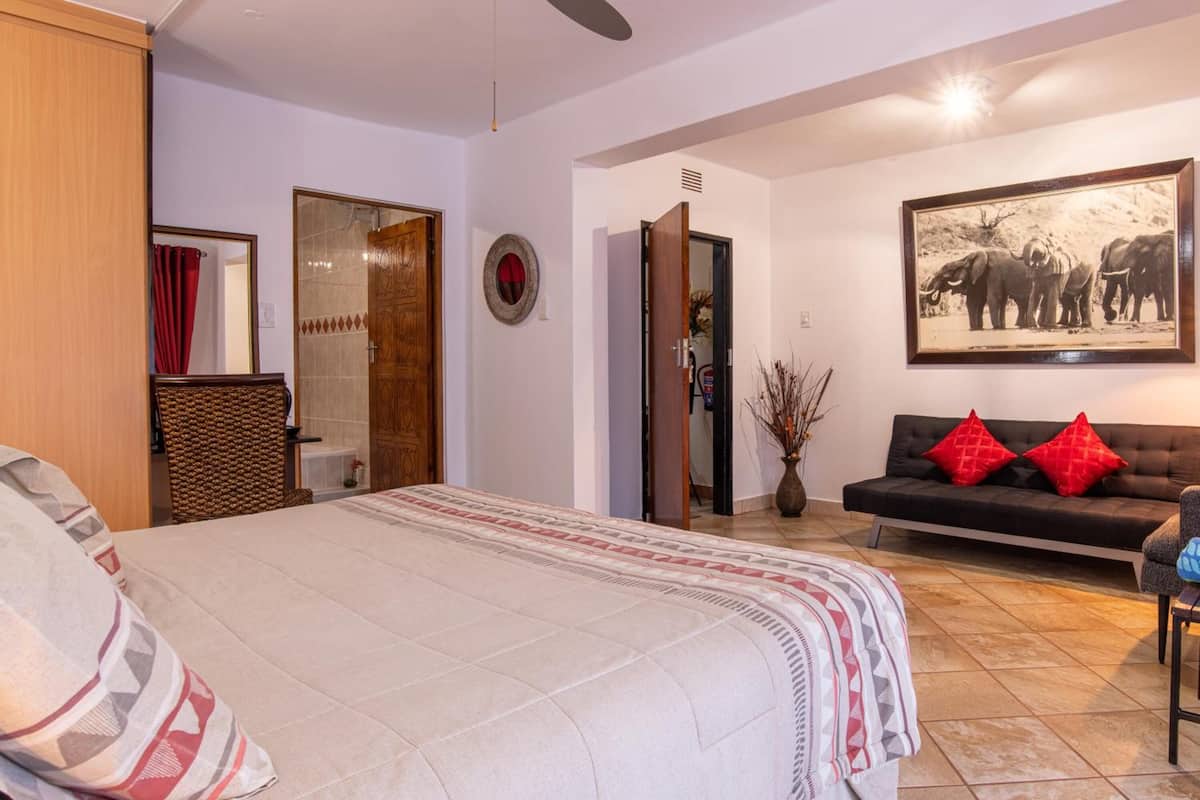Ein Schlafzimmer mit einem Bett, einem Schlafsofa, einem Spiegel und einem gerahmten Bild an der Wand.