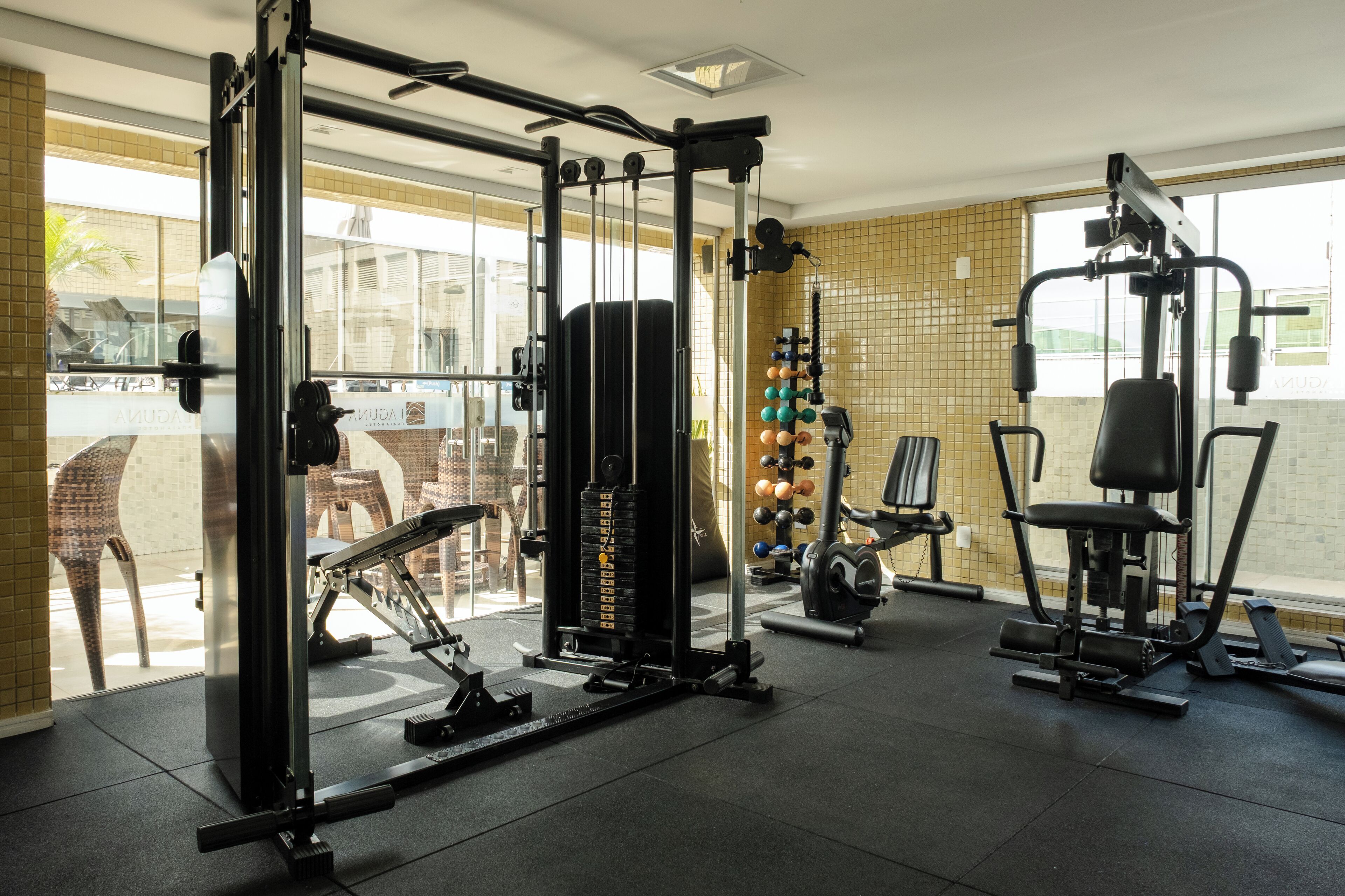 Un gimnasio con varios equipos de ejercicio, incluyendo una estructura para sentadillas, una prensa de banca y una máquina de poleas.