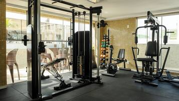 Un gimnasio con varios equipos de ejercicio, incluyendo una estructura para sentadillas, una prensa de banca y una máquina de poleas.
