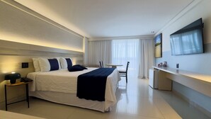 Una habitación de hotel moderna con una cama grande, mesitas de noche, un escritorio y un televisor de pantalla plana.