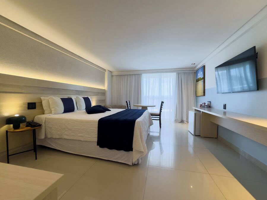 Una habitación de hotel moderna con una cama grande, mesitas de noche, un escritorio y un televisor de pantalla plana.