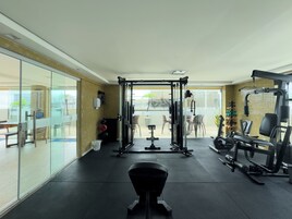 Una palestra con attrezzature per esercizi, una parete in vetro e vista su un'area relax all'aperto.