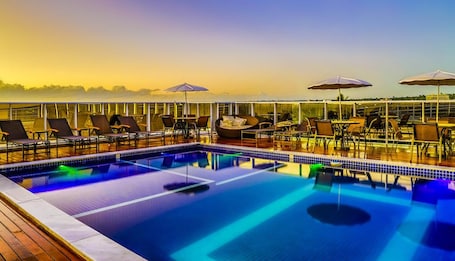 Una piscina al aire libre, sombrillas, sillones reclinables de piscina