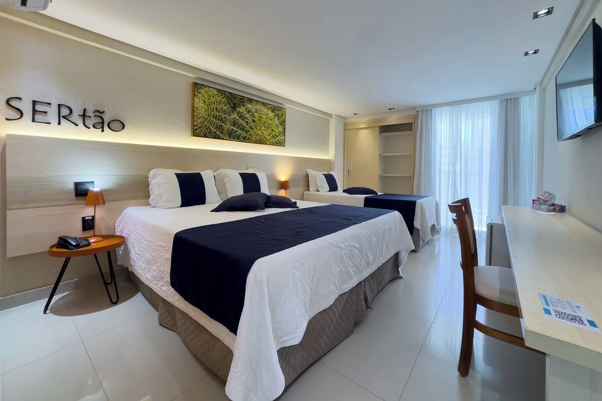 A modern hotel room with two beds, a desk, and a TV.