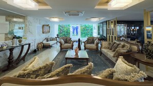 Un salón amplio con un gran ventanal, varios sofás, una mesa de centro y un espejo decorativo.