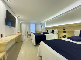 A hotel room with two beds, a desk, a chair, a TV, and a window with curtains.