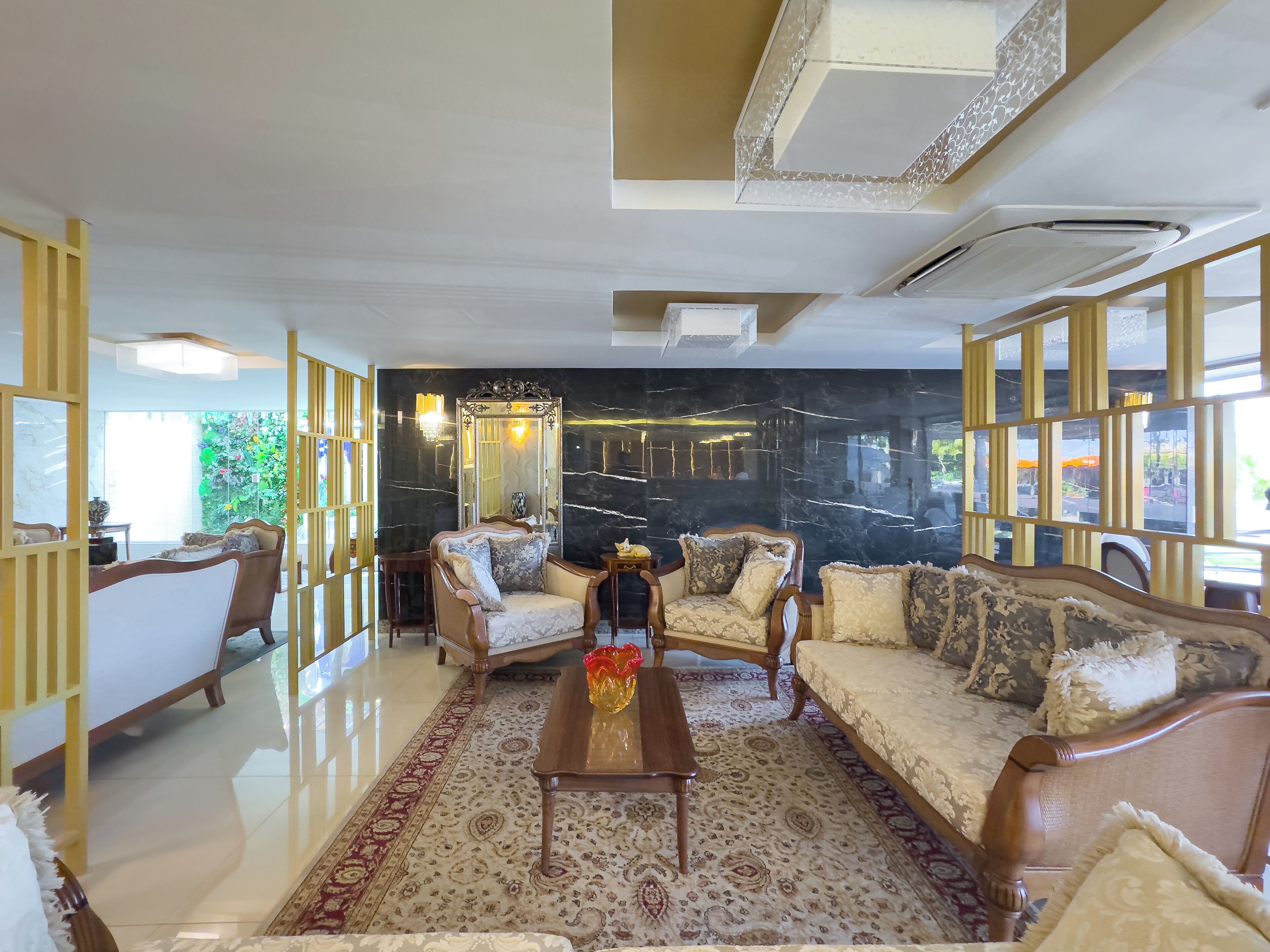 Un amplio salón con un sofá grande, sillones, una mesa de centro y un espejo decorativo.