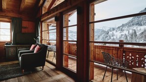 A wooden interior with large windows overlooking a snowy mountain landscape.