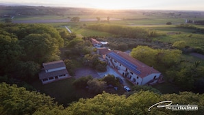 Vista aérea de una extensa propiedad con varias construcciones, rodeada de abundante vegetación y campos.