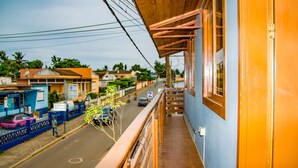 A balcony with a view of a street, a blue building, and a pink car parked on the side. - Porcelana Hotel (São Tomé)