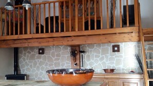 A kitchen with a large copper bowl centerpiece, wooden cabinets, a stone backsplash, and a wooden railing above the counter. - Relaxing Retreat in Saint-Pons (Saint Pons)