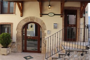 A building entrance with a stone archway, a wooden door, and a metal staircase. - B&B La Fonte (L'Aquila)