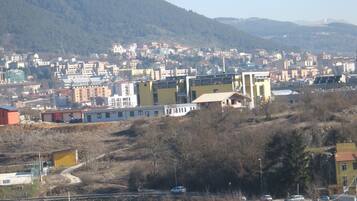Uma cidade com edifícios, uma estrada e um cenário montanhoso.