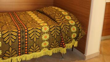 A bedroom with a wooden headboard, a bed with a floral-patterned bedspread, and a mirror above the bed.